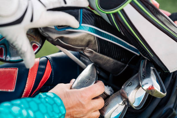 Hands selecting irons from a colorful, well-organized golf bag—close-up of gear prep.
