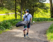 Golfer walking path carrying a golf bag over shoulder—scenic course backdrop.