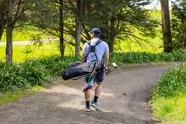 Golfer walking path carrying a golf bag over shoulder—scenic course backdrop.