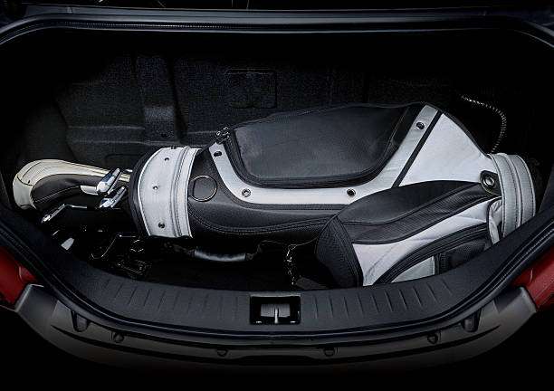 Golf bag and clubs neatly packed in a dark car trunk, ready for travel.