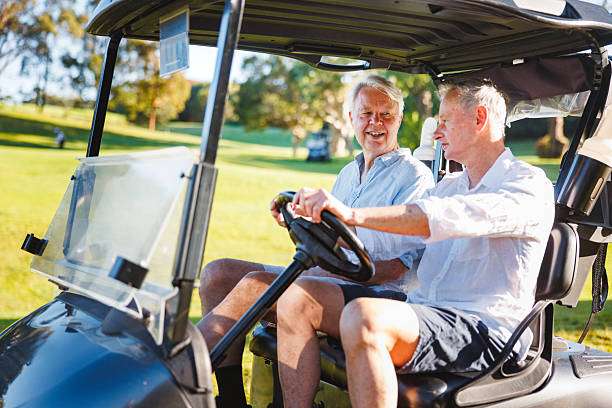 Senior men smiling in a golf cart, ready for a round with their golf bag.