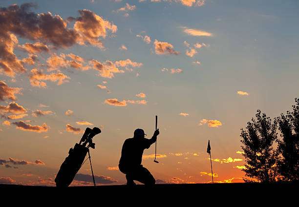 Golfer celebrating a shot on the green with his golf bag at sunset.