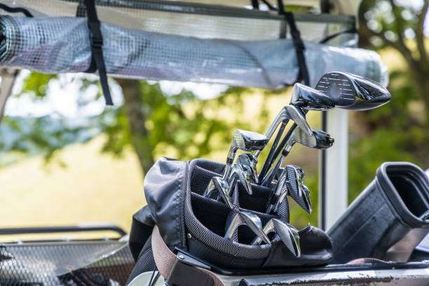 Close-up of shiny golf clubs in a black golf bag on a golf cart.