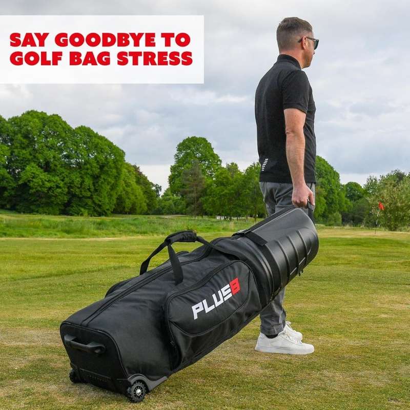 Man pulls a large wheeled black golf bag travel case across a green golf course.